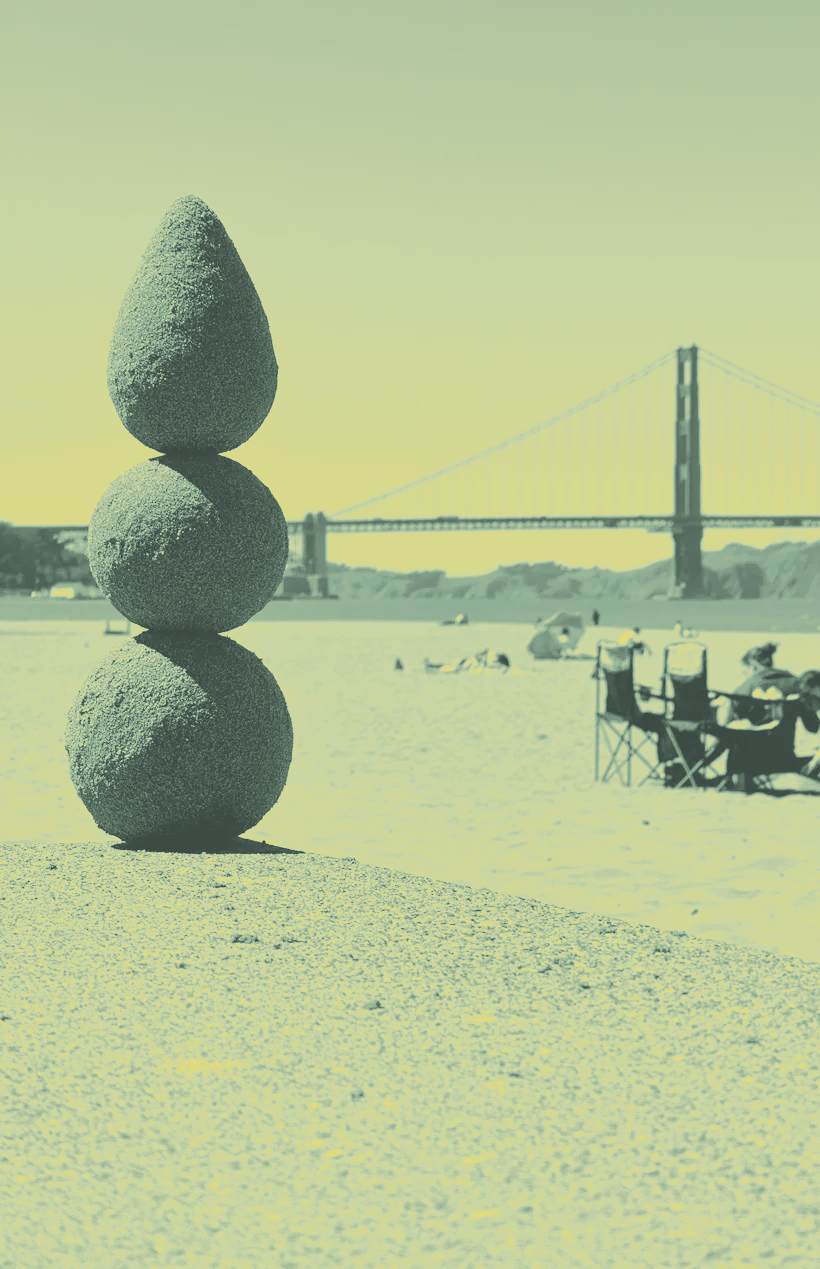 Stacked stones on a beach, with the Golden Gate Bridge in the background